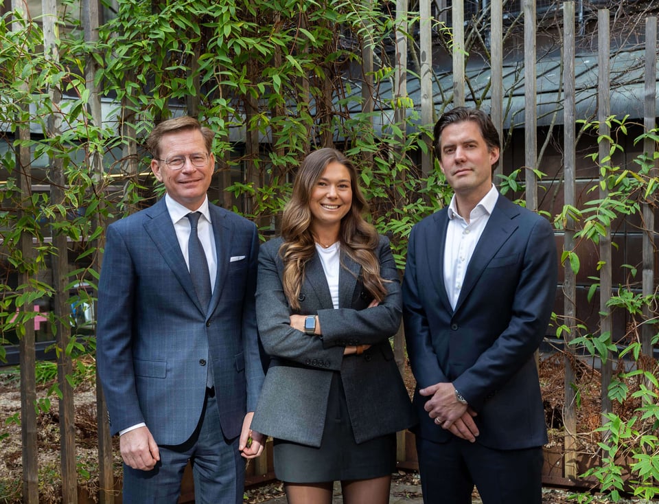 Real Estate teamet på Serafim Finans som består av Anders Wennberg, Felicia Tilander och Robin Sylwander. De står utomhus med grönska bakom sig.